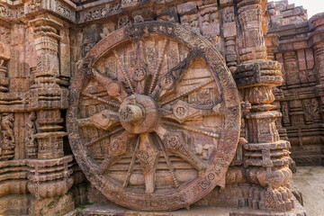 Fototapeta na wymiar A stone wheel engraved in the walls of the 800 year old Sun Temple, Konark, India. The temple is designed as a chariot consisting of 24 such wheels.
