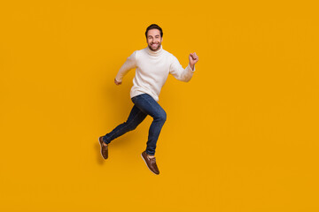 Fototapeta na wymiar Photo of childish pretty guy dressed white sweater running fast jumping high isolated yellow color background