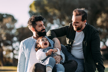 Happy male gay family in the park with their little daughter - Powered by Adobe