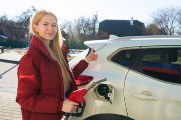 Beautiful young woman refueling her car
