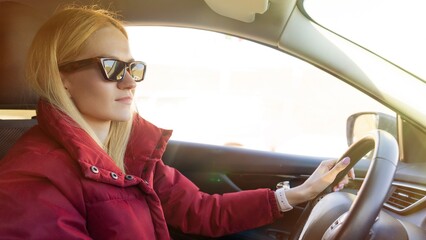A young beautiful woman in sunglasses is driving a car