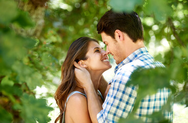 Fototapeta premium Lost in each others eyes. Shot of a young couple sharing a romantic moment in a park.