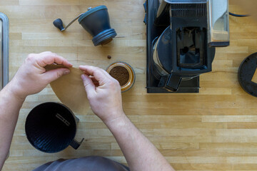Man grinds coffee beans with a traditional coffee grinder using a hand-crank to make the coffee...