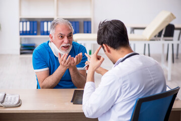 Obraz premium Old neck injured male patient visiting young male doctor