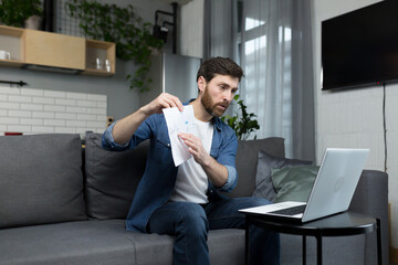 Male freelancer teaches remotely, uses laptop, looks at webcam, explains economic theory to students