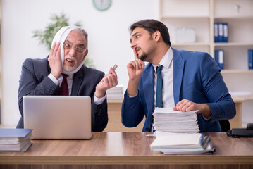 Old male employee suffering from toothache in the office