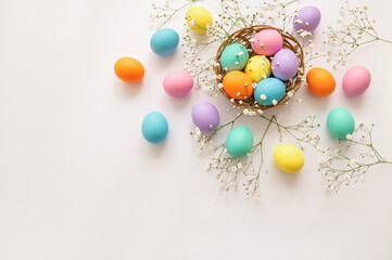 Top view layout of colorful painted Easter eggs with spring flowers on white background. Greeting card for Happy Easter. Copy space for your text.