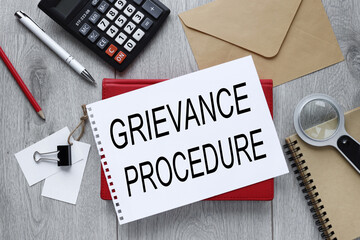 Grievance procedure text on open notepad on red notepad