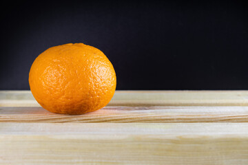 Ripe orange tangerine on board table on dark background, close-up