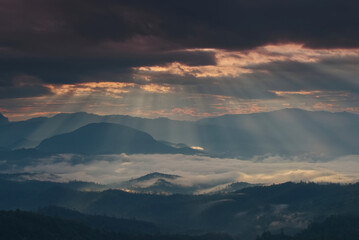 Beautiful sunlight ray over a mountain range and sea of fog in a valley