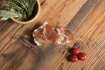 Parma ham on a slice of bread with tomatoes and fresh herbs.