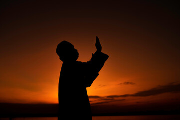 Silhouette Young asian muslim man praying on sunset,Ramadan festival concept