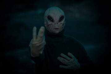 Dark porrait of alien extraterrestrial doing peace and victiry gesture with hands. Stop war and...