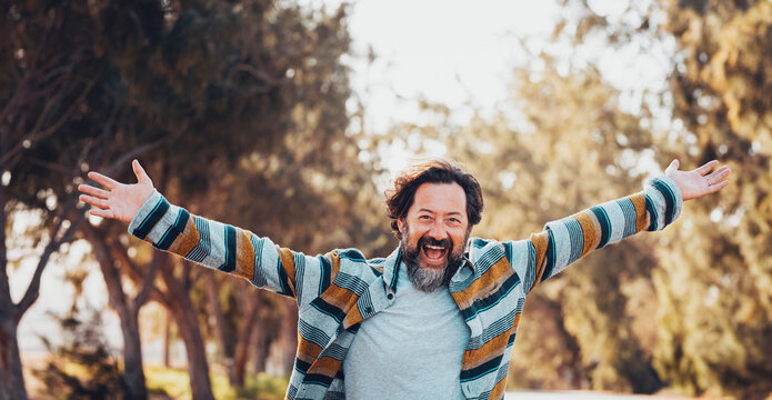 Crazy overjoyed adult man with arms outstretched smile and laugh alone in banner header image. Happiness and joyful people concept lifestyle. Trees and nature for outdoor leisure activity male