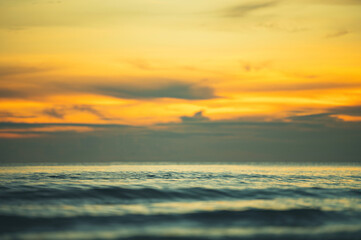 Summer sunset view on the beach. Beautiful blazing sunset landscape and orange sky above it with sun reflection on waves.