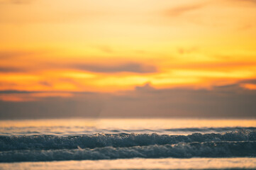 Summer sunset view on the beach. Beautiful blazing sunset landscape and orange sky above it with sun reflection on waves.