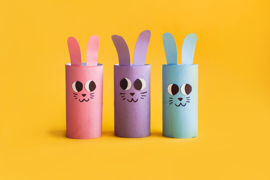 Holiday easy DIY craft idea for kids. Toilet paper roll tube toy's cute rabbit's on yellow background. Creative Easter or Christmas decoration eco-friendly, reuse, recycle handmade minimal concept