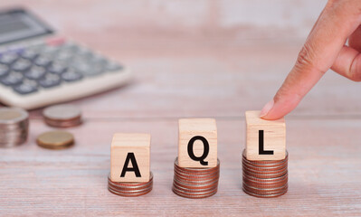 AQL concept, Hand with wooden block with text AQL and calculator. AQL ACCEPTABLE QUALITY LEVEL, pen...