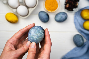 Fototapeta na wymiar Woman's hands hold a painted Easter egg. The process of dyeing Easter eggs with natural dyes at home. Close-up. Top view.