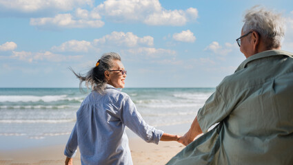 Happy senior woman is enjoying and fun holding hand husband and pull to seaside on beach in vacation summer.