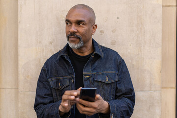 Mature black man in city using cell phone