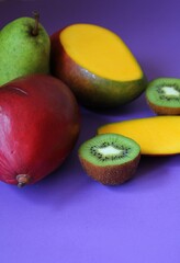fresh fruit, juicy mango, kiwi cut in half, large pear, colors, purple background, vitamins, sweet nature