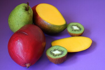 fresh fruit, juicy mango, kiwi cut in half, large pear, colors, purple background, vitamins, sweet nature