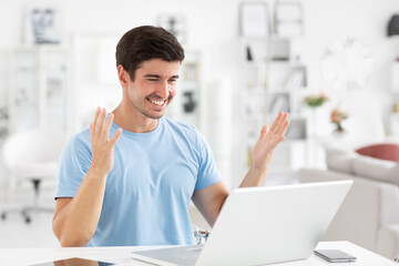 Young cheerful man celebrating victory while looking at laptop screen.