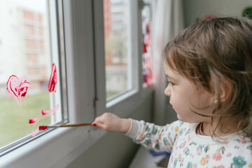 Fototapeta na wymiar Adorable little girl painting a window