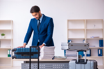 Young male employee preparing for business trip at workplace