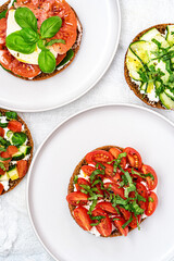 Sandwiches with tomatoes,cucumber,mozzarella,feta and herbs served on white plates. aflat lay. Healthy food concept.