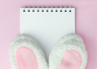 Easter hat bunny ears on pink background on the notebook with copyspace