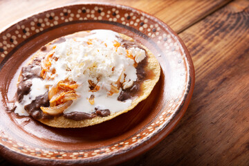 Tostadas de Tinga de Pollo. Traditional mexican homemade chicken toasts with beans, chicken breast meat, onion and chipotle chili topped with sour cream and fresh white cheese
