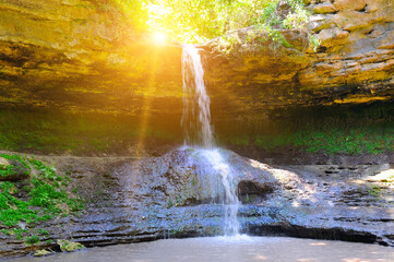Fototapeta na wymiar Beautiful waterfall in the forest and sun