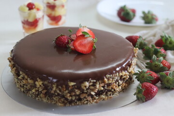Chocolate cake with chocolate ganache and topped with walnut and fresh strawberries