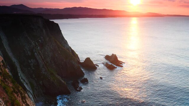 Sunset over rocky cliffs at Asturias coast in north Spain. View from Faro de Cabo Busto. Tourist attraction, place to visit.