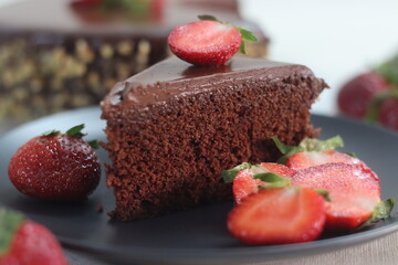 Chocolate cake slice. Chocolate cake with chocolate ganache and topped with walnut and fresh strawberries