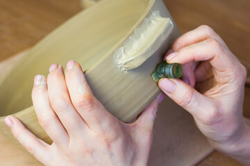Artist pressing seal to ceramic pot. Potter printing stamp with trademark