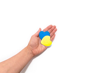 Two hearts in the colors of the flag of Ukraine in female hands. Concept of ending the war in Ukraine