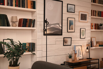 Home library interior with collection of different books on shelves and beautiful pictures