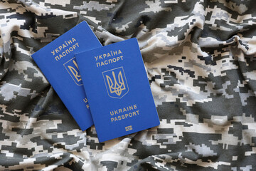Ukrainian foreign passport on fabric with texture of military pixeled camouflage. Cloth with camo...