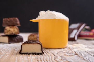 a sweet bar made of whey protein next to a scoop of protein powder for sports nutrition.