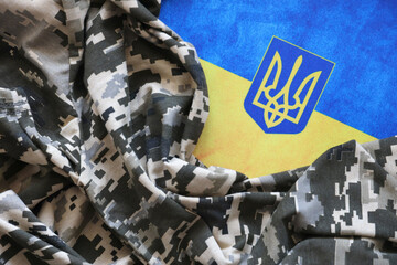 Ukrainian flag and coat of arms with fabric with texture of pixeled camouflage. Cloth with camo...