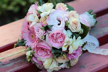 wedding bouquet consists of white, pink, purple flowers, green leaves, gerbera flowers, peony roses on old wooden background with peeling red paint, beautiful and colorful bouquet of flowers