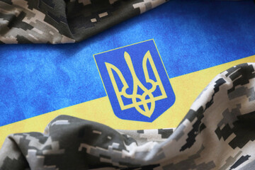 Ukrainian flag and coat of arms with fabric with texture of pixeled camouflage. Cloth with camo...