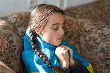 little girl covered with Ukraine flag. Concept of standing with Ukrainian nation in war with Russia.