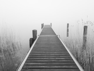 The jetty on the foggy lake, in shades of grey