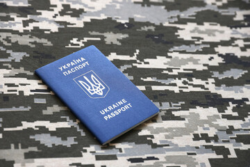 Ukrainian foreign passport on fabric with texture of military pixeled camouflage. Cloth with camo...