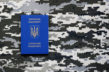 Ukrainian foreign passport on fabric with texture of military pixeled camouflage. Cloth with camo...