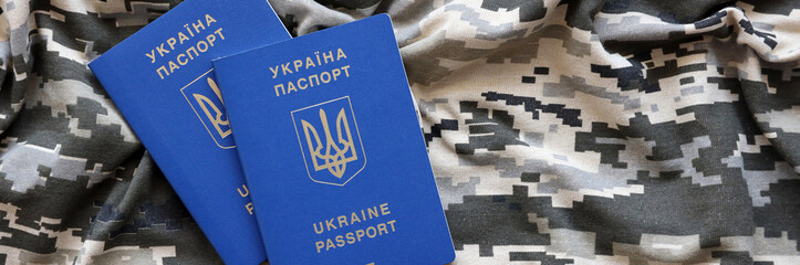 Ukrainian foreign passport on fabric with texture of military pixeled camouflage. Cloth with camo...